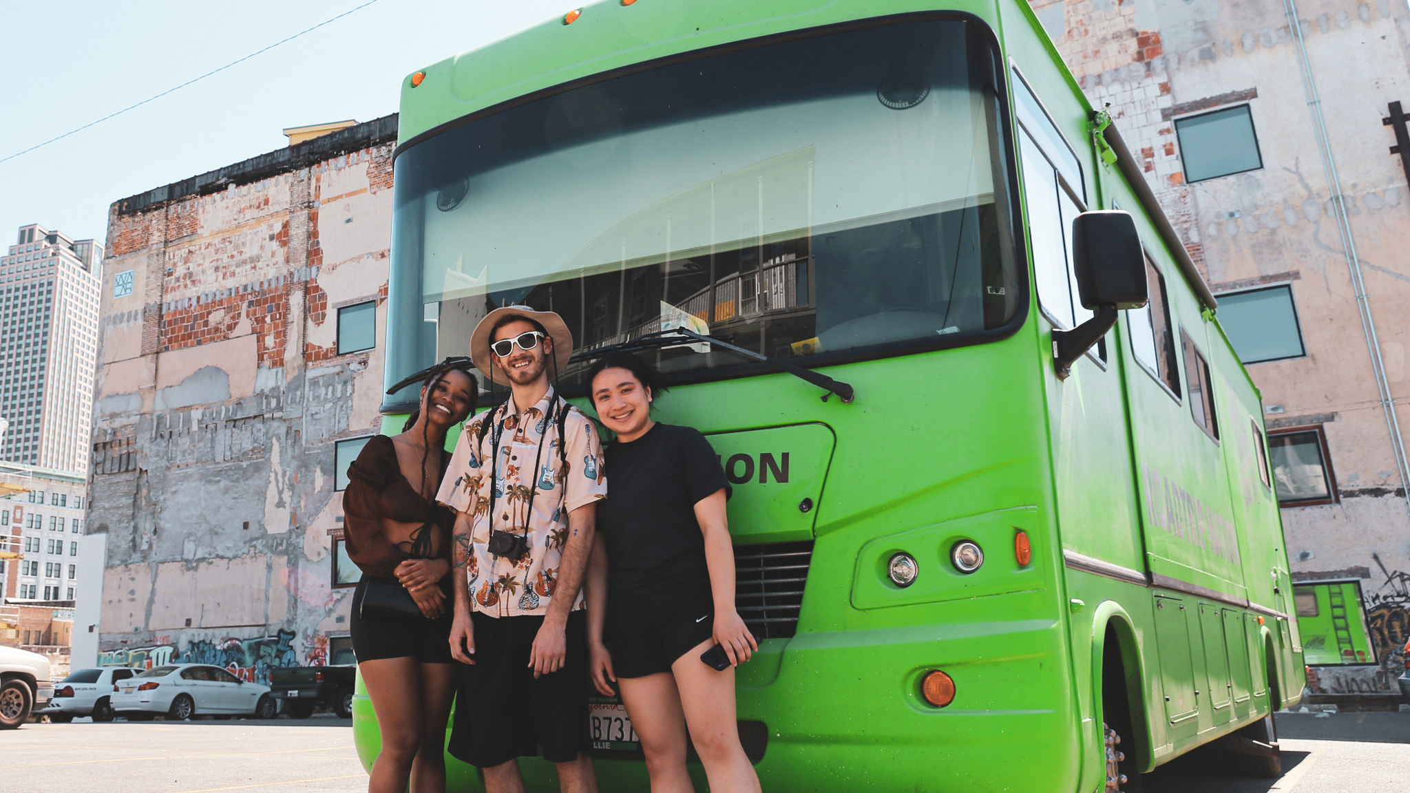 From left, roadtrippers Rahael, Jake, and Genevieve pose in front of the green RV.